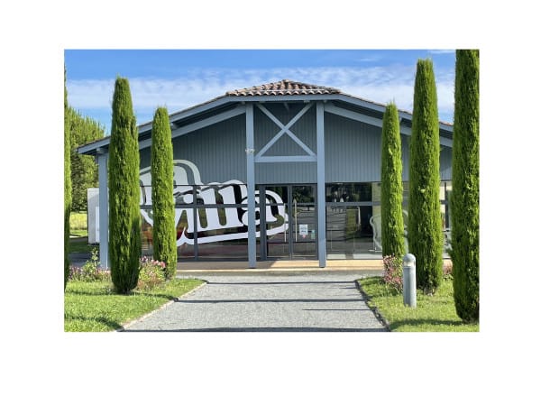 La Villa : bâtiment contemporain en bardage gris à charpente apparente, encadré de cyprès, le mot « Villa » peint en grand sur la façade vitrée.